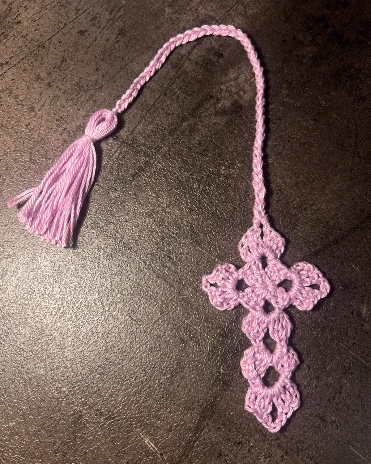Segnalibro crochet rosa con nappina su superficie scura